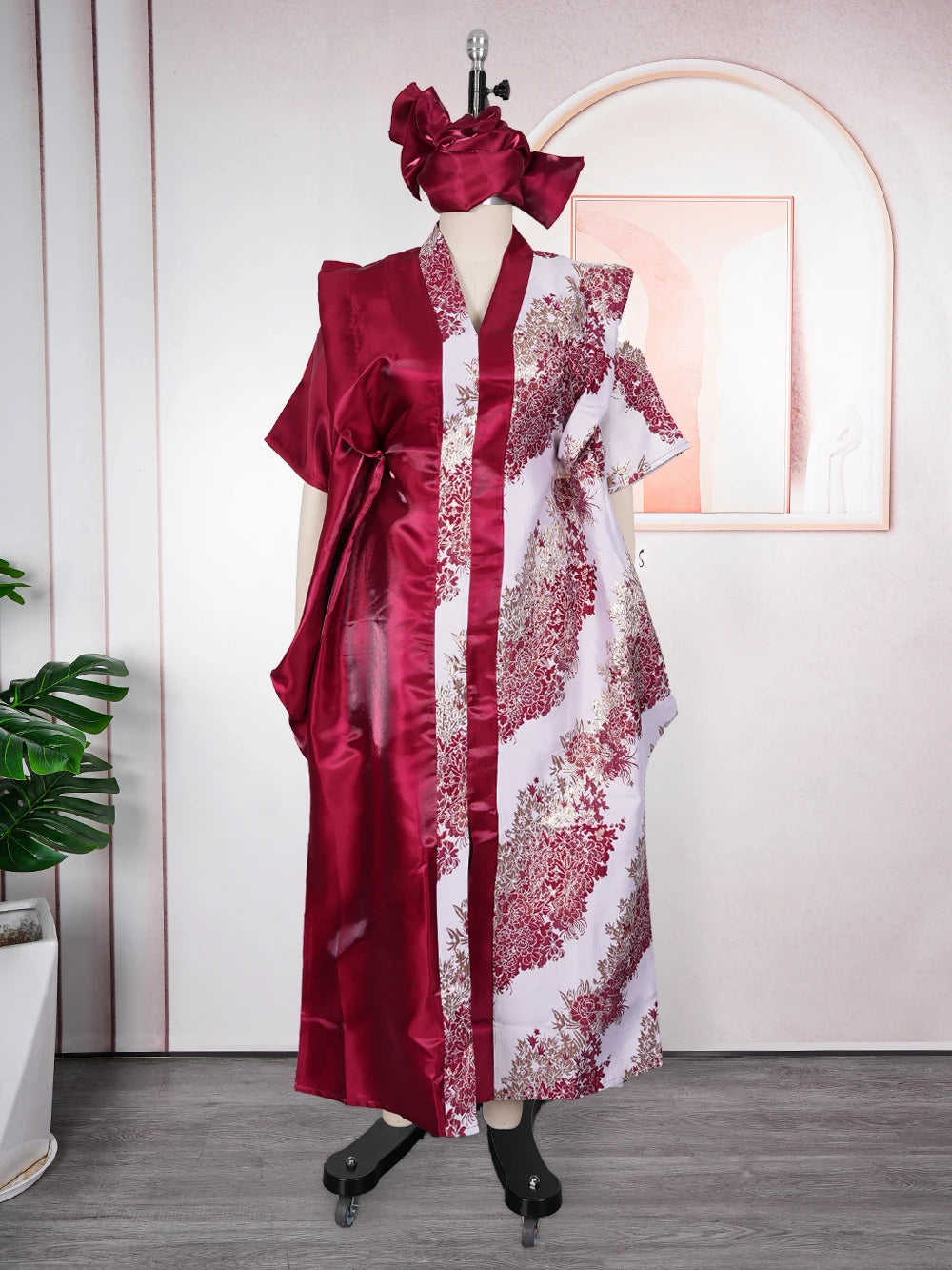 A woman wearing an elegant flowing kaftan dress in deep red and white with floral tatting detail.