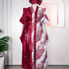 A woman wearing an elegant flowing kaftan dress in deep red and white with floral tatting detail.