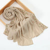 A beige chiffon hijab shawl with delicate pink floral embroidery draped over a wooden frame.