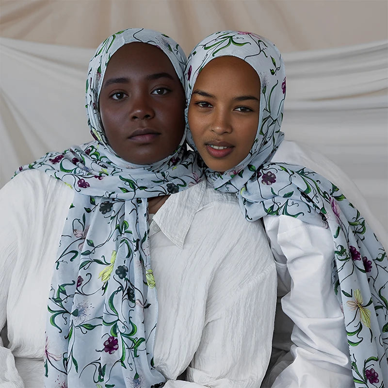 Une femme portant un hijab bohème à imprimé léopard bleu clair et des vêtements blancs.