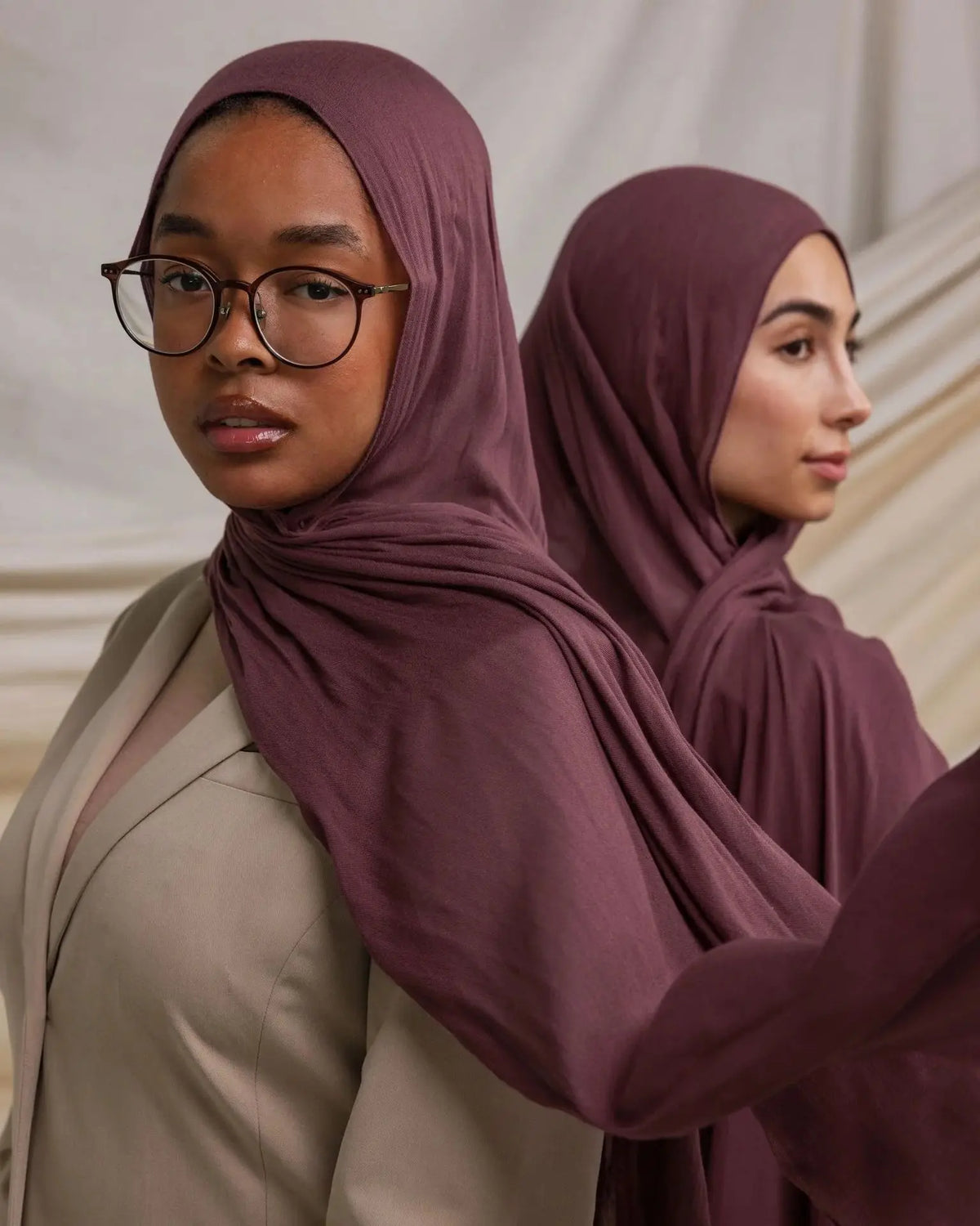 Une femme portant un foulard modal de couleur rose poudré et un haut beige, regardant directement l'appareil photo.