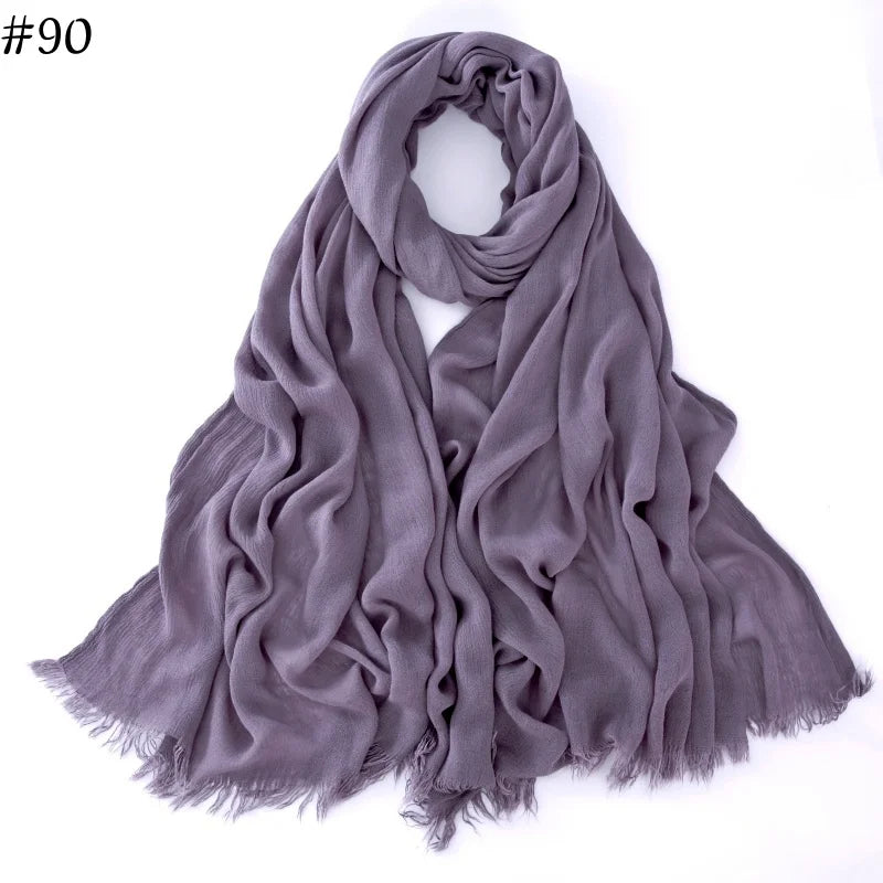 Foulard hijab en coton viscose gris doux, drapé et plié, avec des bords effilés.