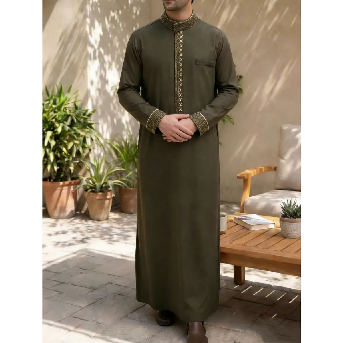 Un hombre vistiendo una jubba tradicional islámica de color verde oliva oscuro al aire libre.