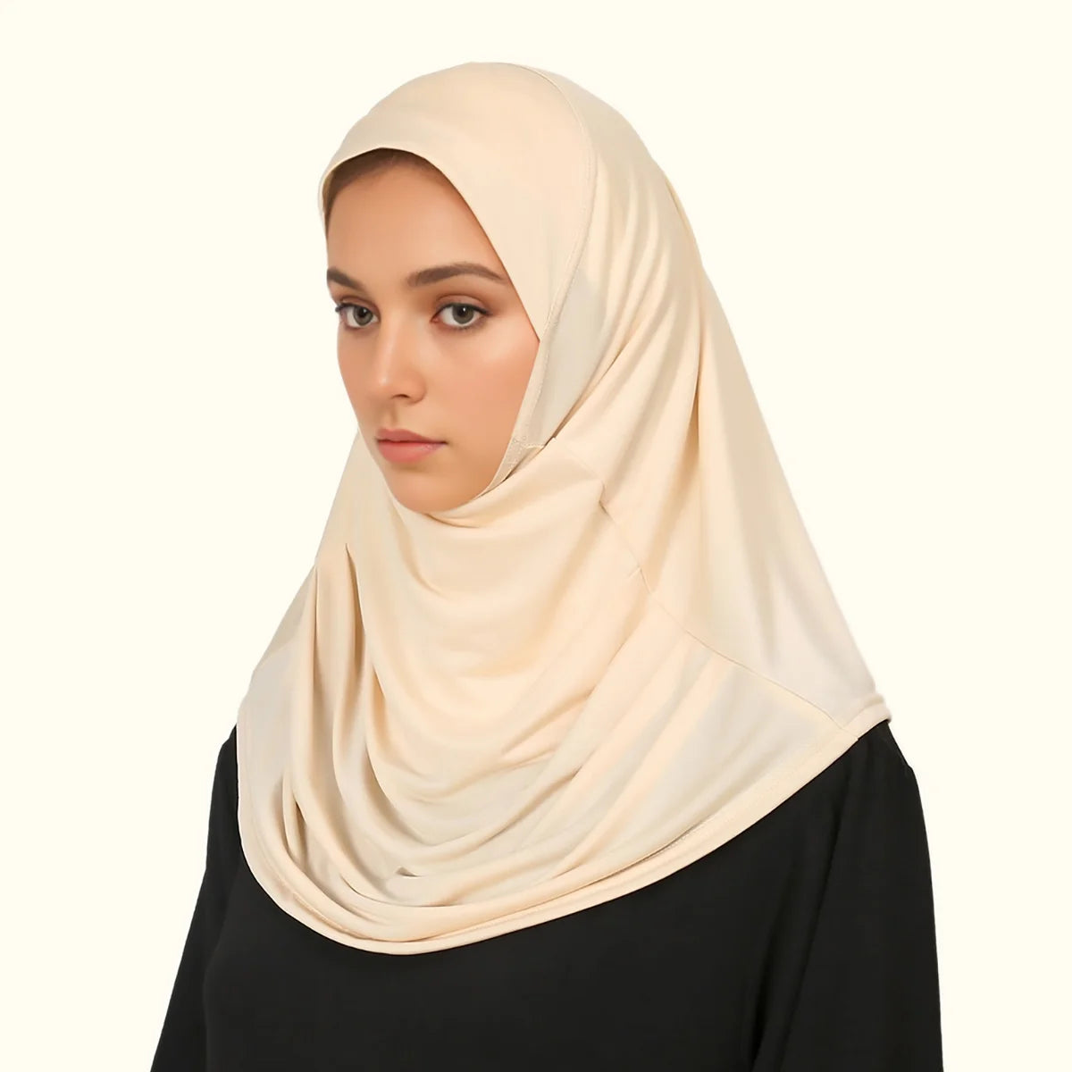Eine Frau trägt einen beigen, sofort einsatzbereiten Hijab und ein schwarzes Oberteil.