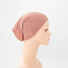 Helle, staubrosa Bambus-Jersey-Turban-Kappe auf einem Mannequin-Kopf.