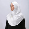 Une femme portant un foulard hijab brodé or et blanc sur un fond gris clair.