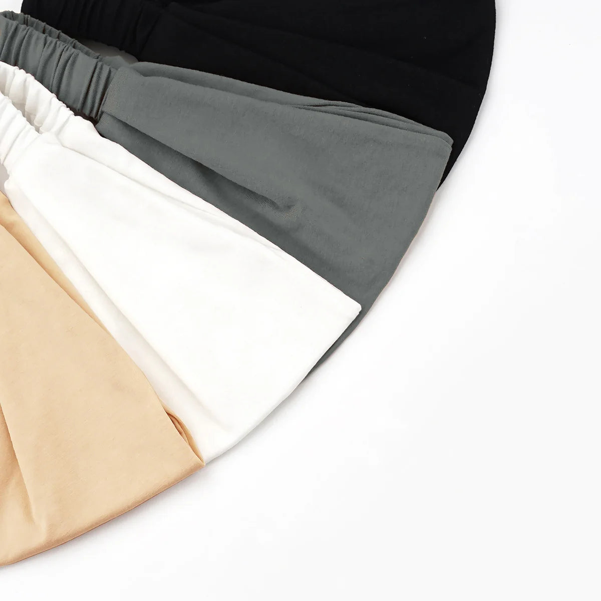 Stapel weicher Baumwoll-Stretch-Hijab-Caps und -Headbands in Schwarz, Grau, Weiß und Beige.