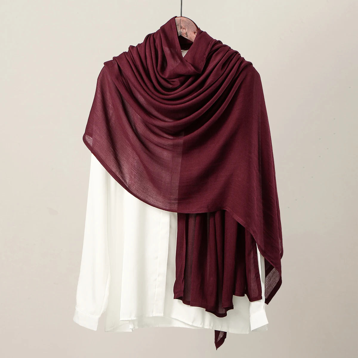 Pañuelo hijab de modal rayón color borgoña intenso sobre una blusa blanca.