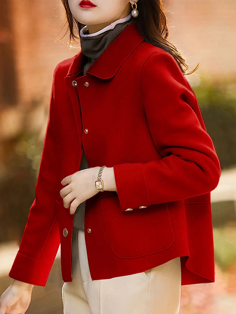 Une femme portant un manteau en laine rouge vif sur un haut gris et un pantalon clair.