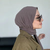 Una mujer vistiendo un hiyab instantáneo color malva polvoriento y gafas de sol, mirando hacia un lado.