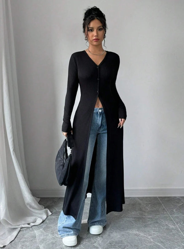 A woman models a black ribbed knit maxi cardigan over blue jeans in a studio setting.