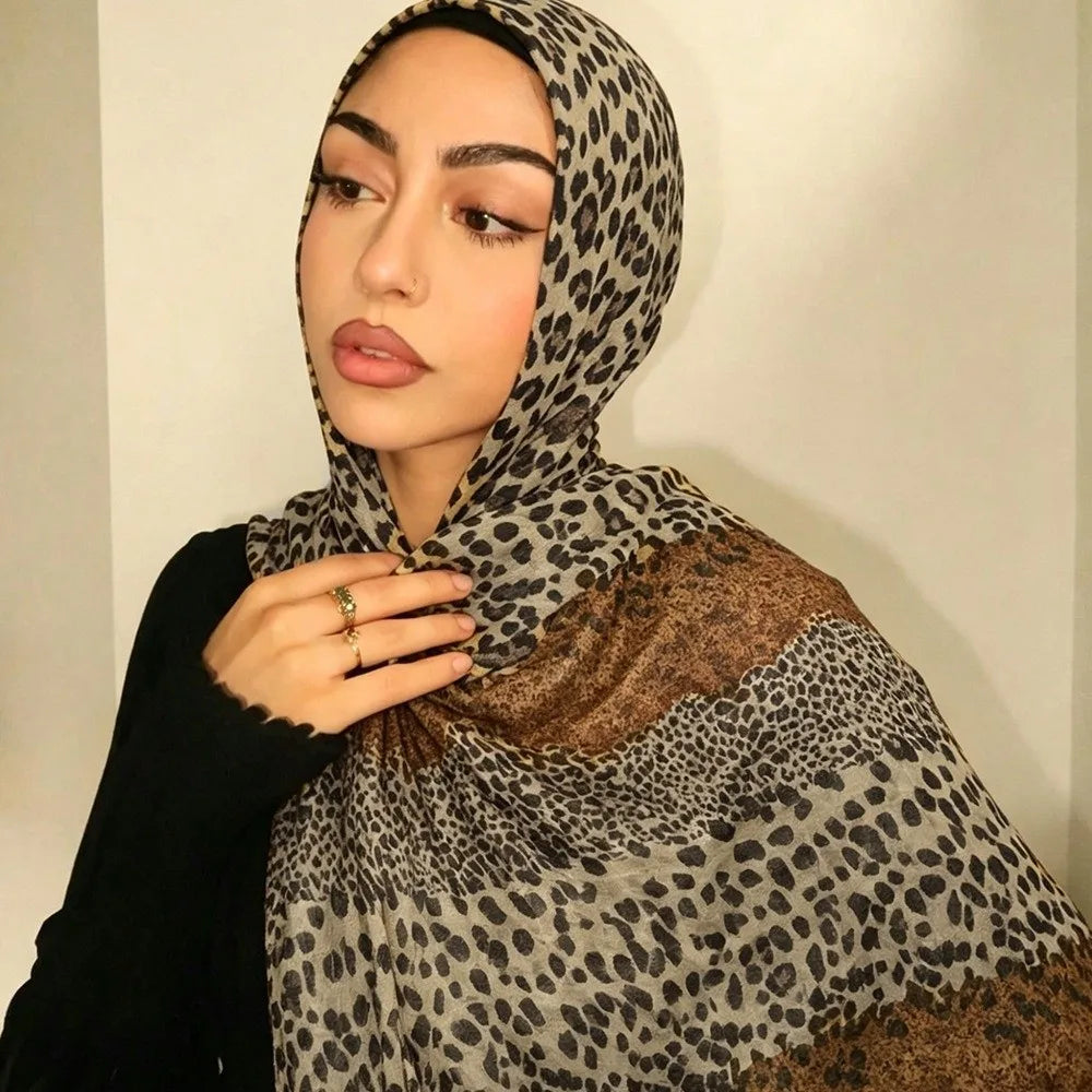 Eine Frau trägt einen Leopardenmuster- und Polka-Dot-Baumwollschal mit einem schwarzen Oberteil.