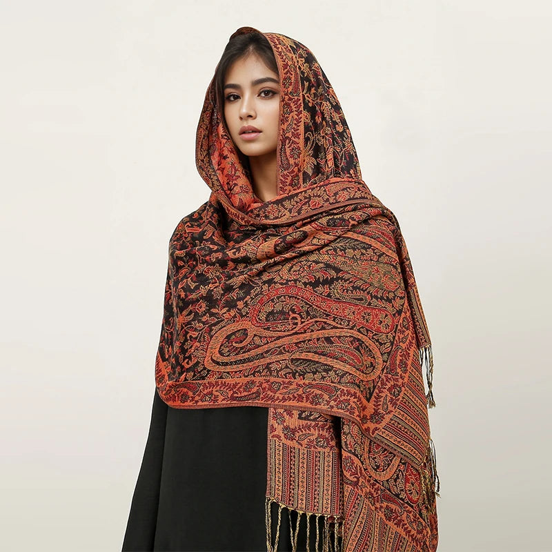 Una mujer vistiendo un pañuelo pashmina de lujo, con patrones terracota y negro, sobre su cabeza.