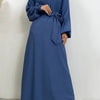 Eine Frau trägt ein langes, marineblaues marokkanisches Kaftan-Abaya mit schwarzen Ärmeln und einem schwarzen Hijab.