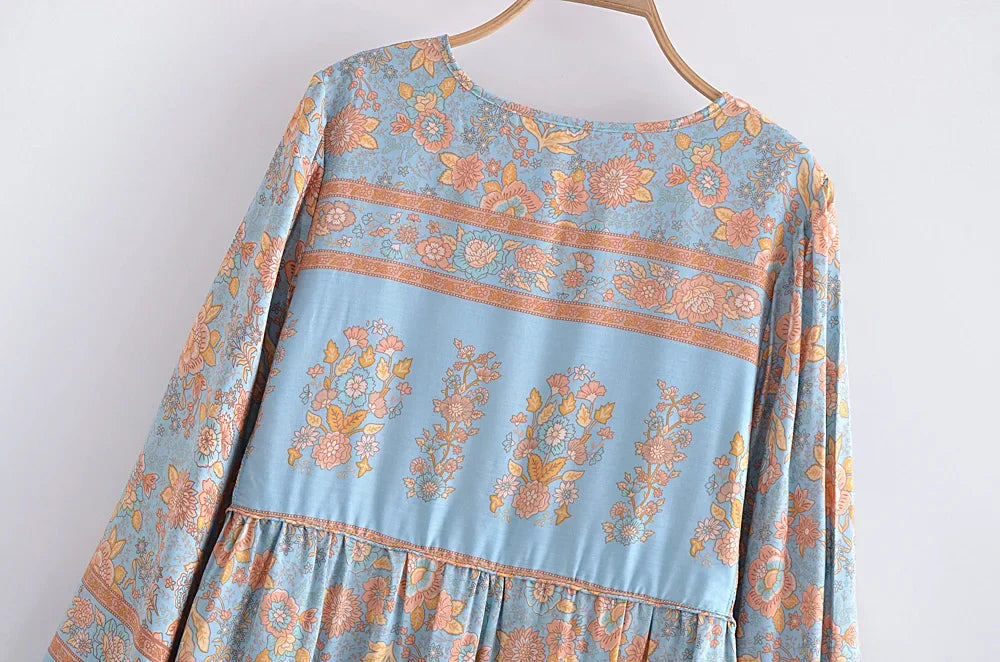 A light blue bohemian floral maxi dress featuring intricate orange and pink patterns and lantern sleeves.