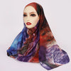 Ein Modell trägt einen dezenten, aquarellartigen floralen Hijab mit lila, rot und blauen Farbtönen.