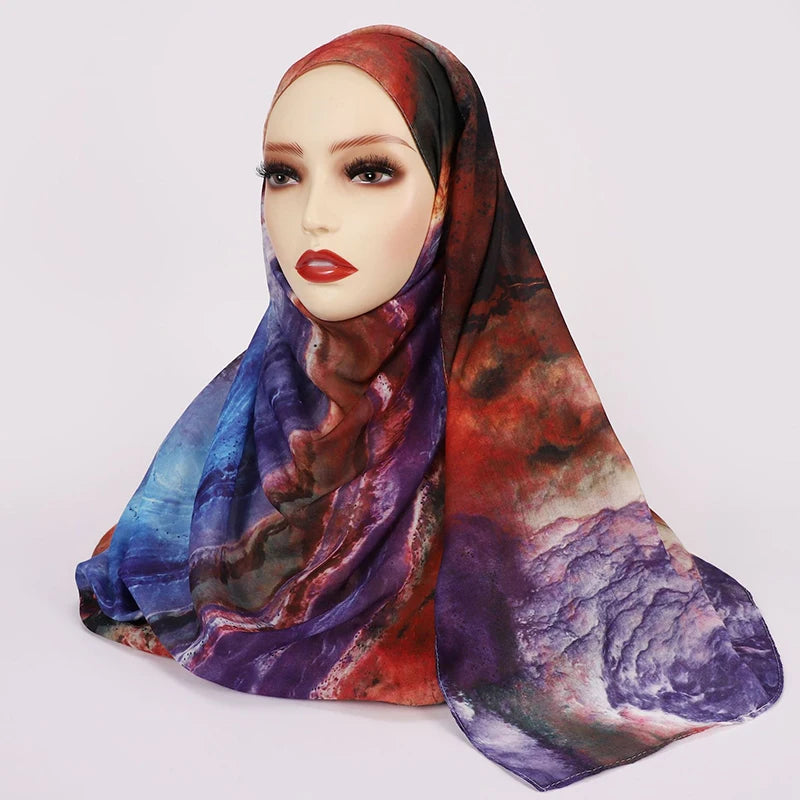 Ein Modell trägt einen dezenten, aquarellartigen floralen Hijab mit lila, rot und blauen Farbtönen.