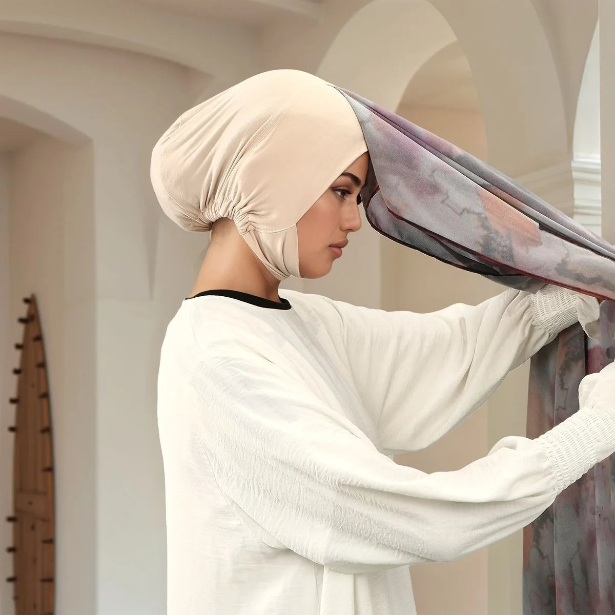 Eine Frau trägt einen beigen Aquarell-Chiffon-Instant-Hijab mit schwarzem Rand und magnetischer Verschlussschnalle.