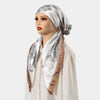 Una mujer modela un turbante instantáneo de hijab estampado floral de satén en tonos plata y marrón.