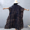 Eine Frau in einem dunkelblauen und beigen gemusterten Sommer-Strandkimono-Überkleid, von hinten gesehen.