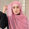 Una mujer con un hiyab rosa transparente sostiene la tela para mostrar una cinta corporal invisible para reparar bufandas y v