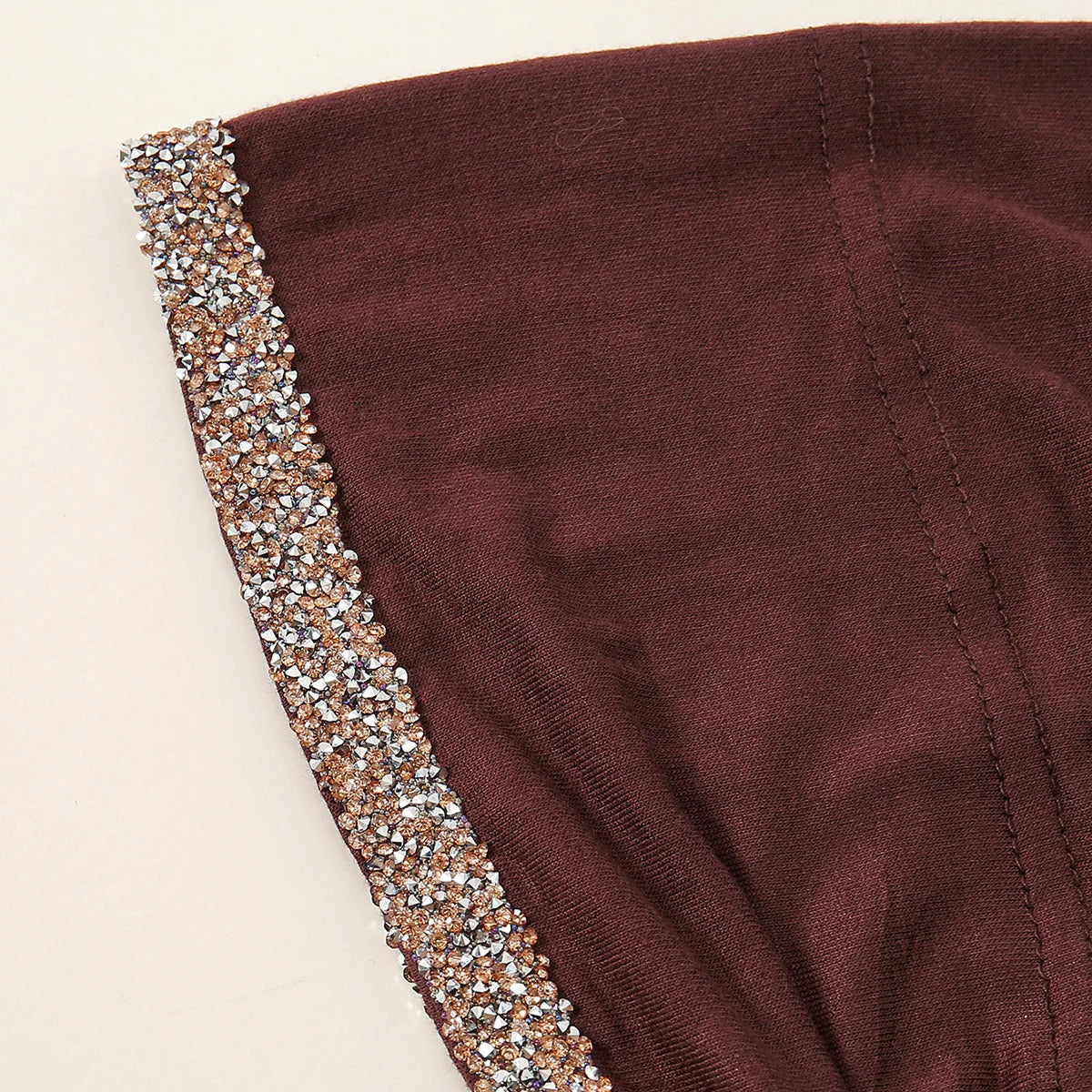 Nahaufnahme eines dunkelmaronen muslimischen Hijab-Schals mit funkelnder Strassverzierung am Rand.