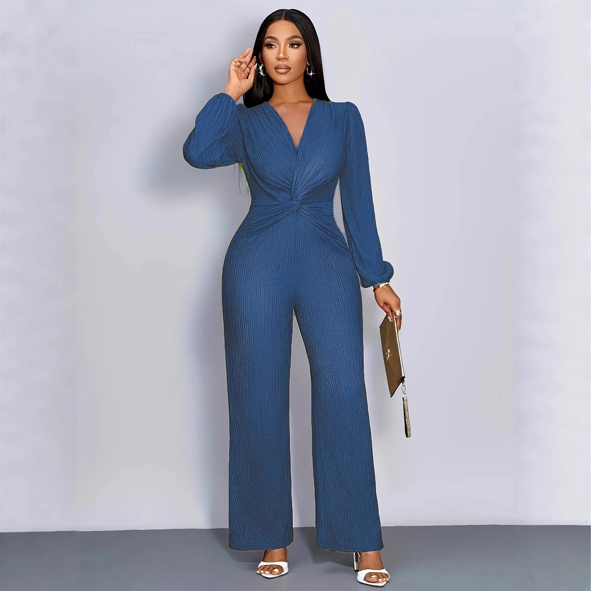 A woman models a long-sleeved, deep V-neck ribbed knit jumpsuit in blue denim.