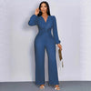 A woman models a long-sleeved, deep V-neck ribbed knit jumpsuit in blue denim.