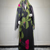 Un conjunto abaya de gasa negra con estampado floral verde y toques rosa, exhibido en maniquí.