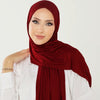 Una mujer vistiendo un pañuelo hijab de algodón premium elástico color granate intenso con una blusa blanca.