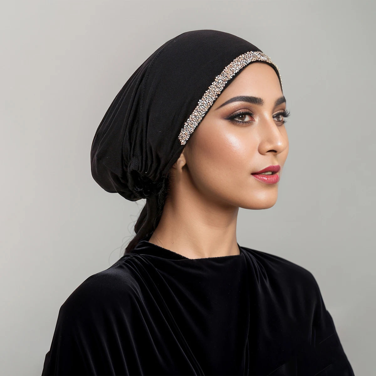 Eine Frau trägt einen schwarzen Samt-Hijab mit einem funkelnden Strass-Detail auf der Stirn.