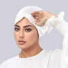A woman wearing a white adjustable elastic headband hijab cap and white top, looking directly at the camera.