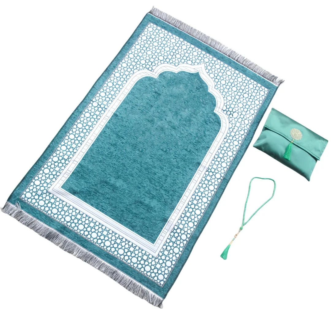 Un tapete de oración verde azulado con bordado blanco y flecos, junto con una bolsa a juego.