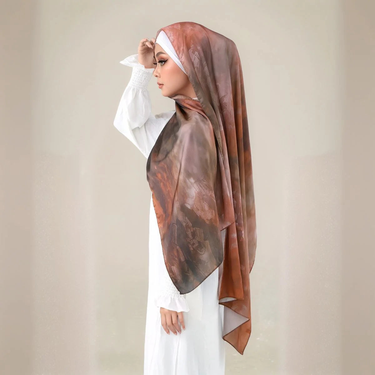 Eine Frau trägt einen braunen schimmernden Satin-Seid-Hijab-Schal über ein weißes Kleidungsstück.