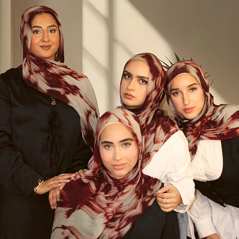 Vier Frauen tragen bescheidene Hijabs mit einem aquarellartigen Blumenmuster-Schal in Maron- und Beigetönen.