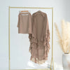 A beige ruffled two-layer chiffon hijab displayed on a gold hanger against a white background.