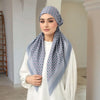 Eine Frau trägt einen hellblauen floralen Voile-Hijab und ein weißes Oberteil.