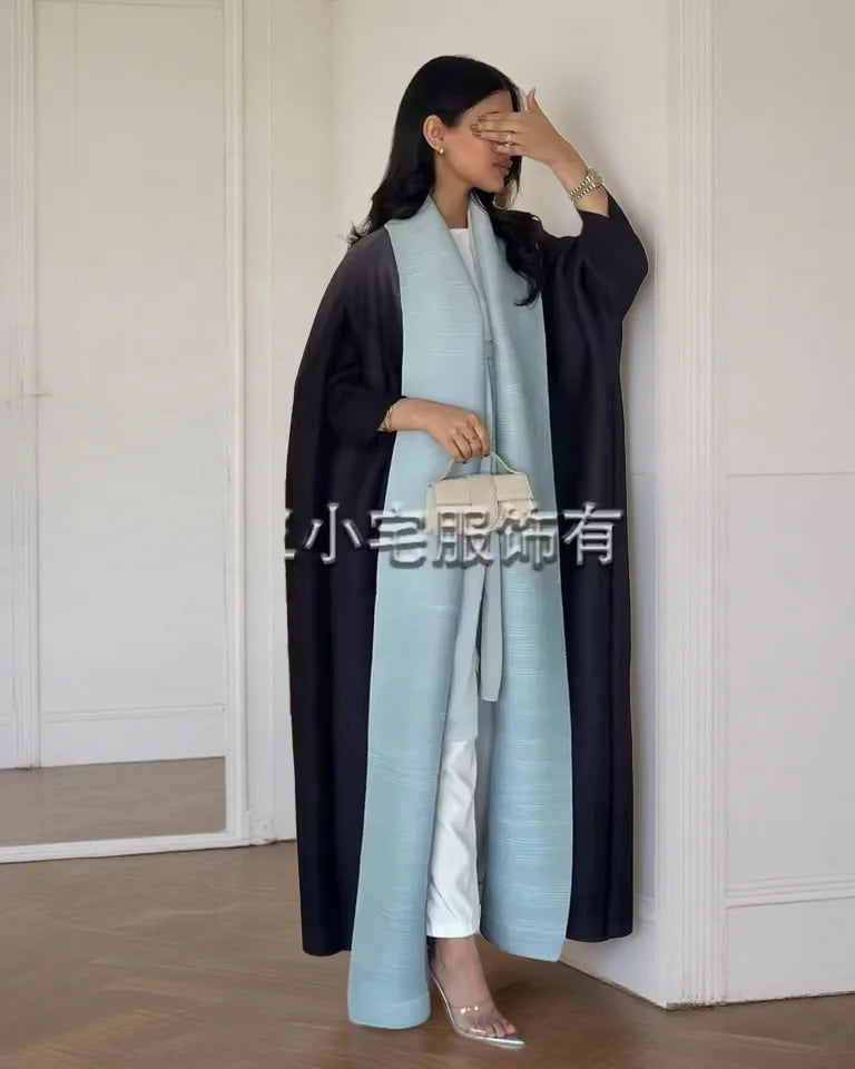 Una mujer vistiendo un cárdigan abaya plisado largo y azul claro sobre una prenda negra.
