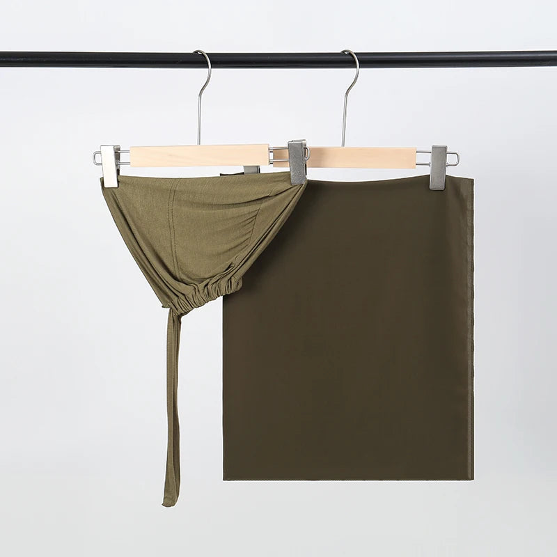 Olivgrüner Chiffon-Hijab und Untercap-Set hängt an einem schwarzen Stäbchen.