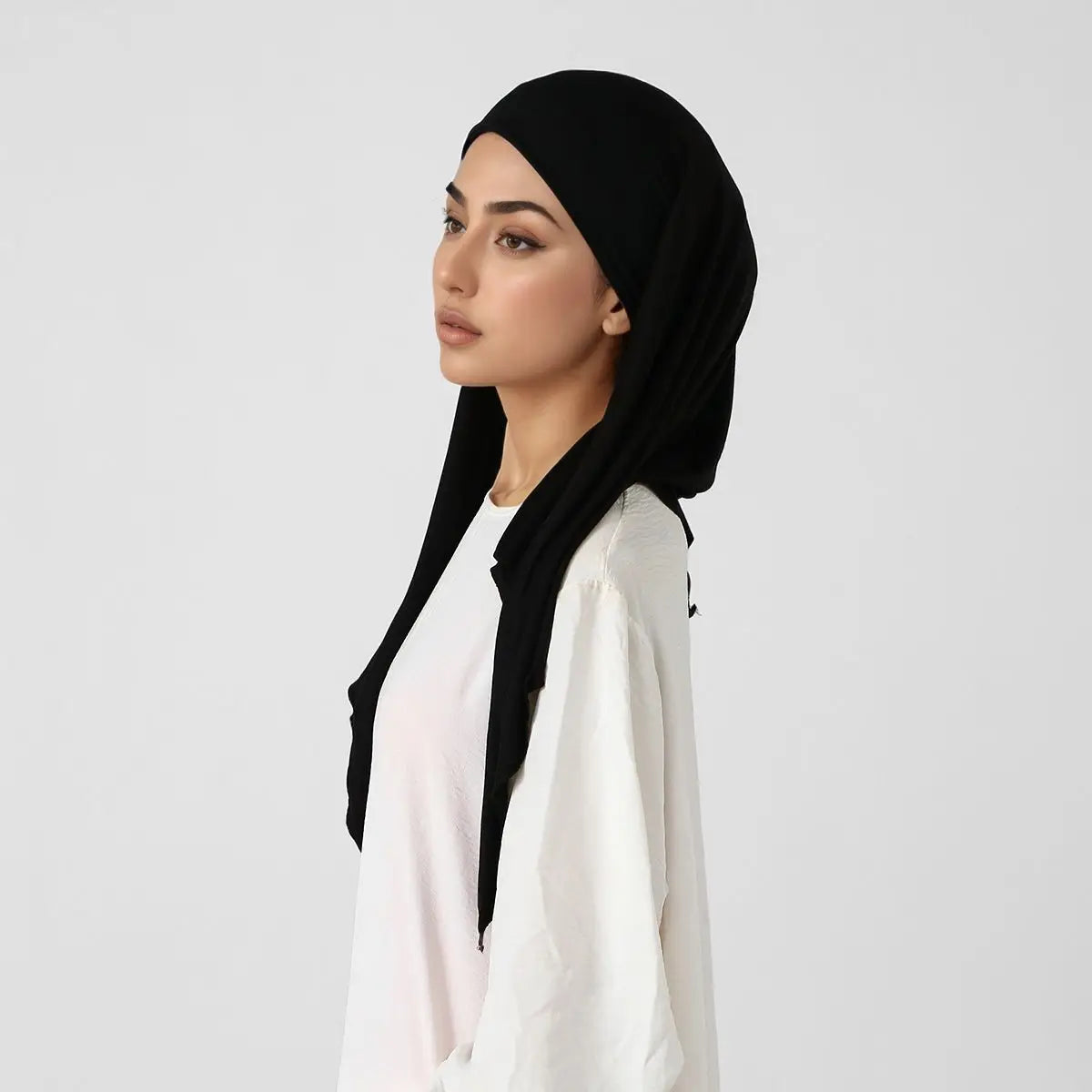 Une femme portant un foulard triangle élégant noir et un haut blanc.