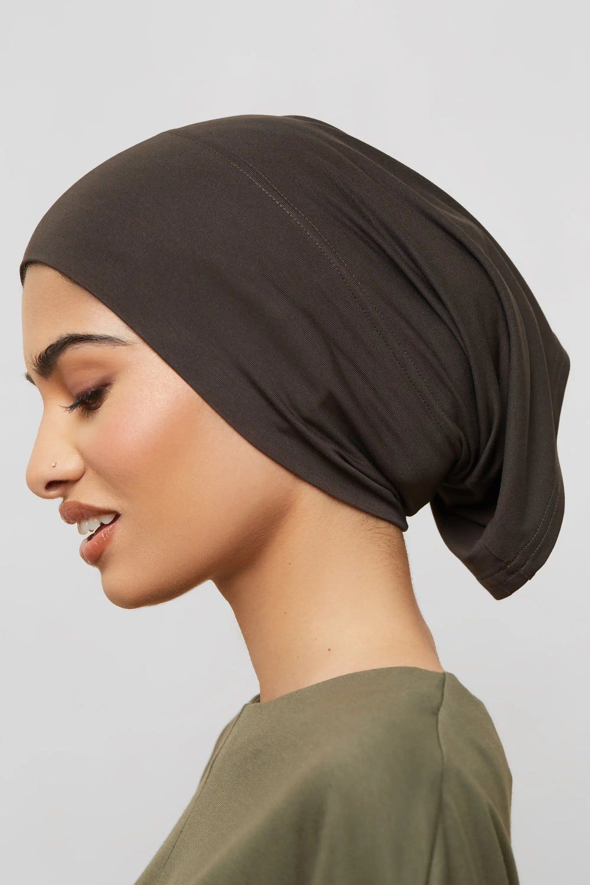 Nahaufnahme einer Frau mit einem einfarbigen dunkelbraunen Bambus-Jersey-Turban-Cap.