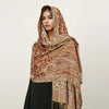 Una mujer modela un pañuelo pashmina de lujo marrón y beige drapeado sobre su cabeza y hombros.