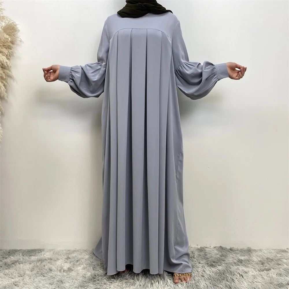 Eine Frau modelliert ein elegantes, langes, lockeres graues islamisches Kleid mit langen Ärmeln.