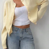 Une femme portant un pull en tricot jaune sur un haut côtelé blanc et un jean bleu.
