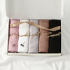 Eine Box mit fünf Jersey-Hijab-Schals in Pink, Weiß, Beige und Schwarz, mit natürlichen Binden