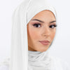 Une femme portant un hijab en mousseline instantanée blanche, regardant directement l'appareil photo.