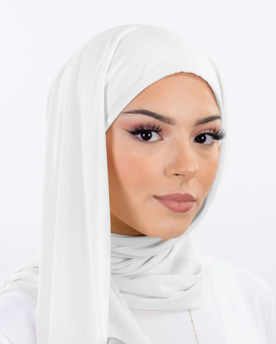 Une femme portant un hijab en mousseline instantanée blanche, regardant directement l'appareil photo.