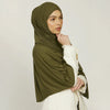 A woman wearing an olive green stretchy jersey plain hijab scarf with a white textured sleeve.