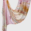 A flowing, sheer linen hijab scarf featuring soft pink and beige floral prints draped elegantly.