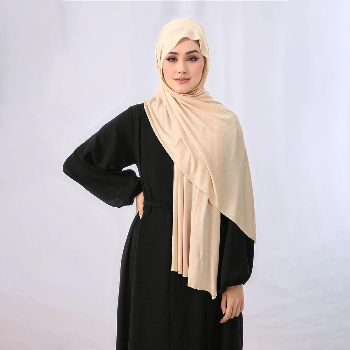 Eine Frau trägt ein beige elegantes Modal-Jersey-Hijab und ein schwarzes Kleid.
